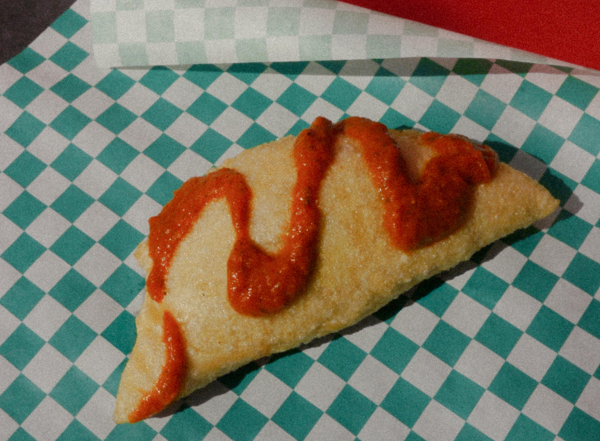 Pizza Fritta with marinara drizzle on checkered deli paper